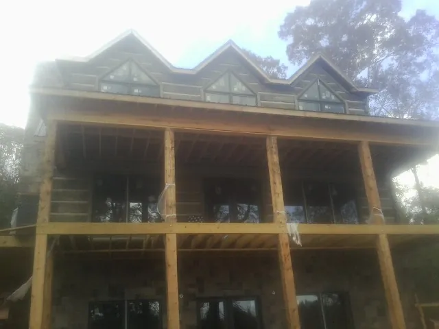 Dormers and porch framing on a large log home under construction — Roof Coating work by our crew in Mitchell